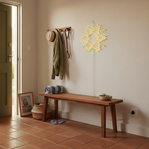 LED snowflake motif light mounted on a textured wall above a wooden bench in a cozy entry alcove.