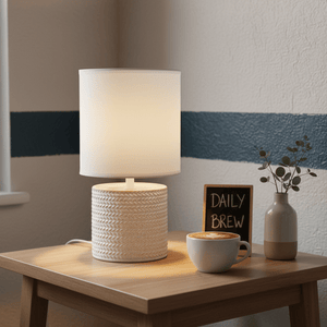 Valencia White Table Lamp on a wooden side table with a coffee cup and decorative plant.