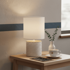 Valencia White Table Lamp on a wooden side table with a coffee cup and plant, creating a cozy ambiance.