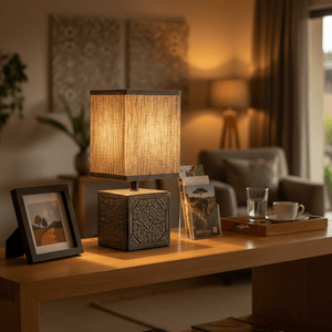 A stylish table lamp with a textured shade on a wooden table, surrounded by decor items.