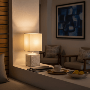 A contemporary white table lamp with a ceramic base, softly illuminating a cozy living space.