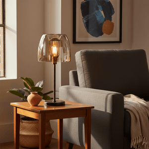 Campbell Cognac Table Lamp on a wooden side table beside a grey armchair, with a plant and decorative vase.