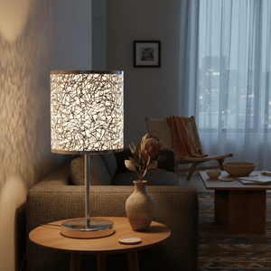 Polished chrome table lamp with silver patterned shade on a wooden side table, illuminating a cozy living room scene.