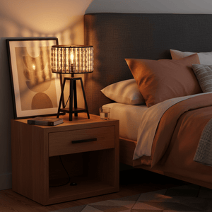 A stylish metal and wood bead table lamp on a bedside table, casting a warm glow in a cozy bedroom setting.