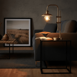 Finique Brass Table Lamp on a black side table beside a sofa, illuminating an open book.