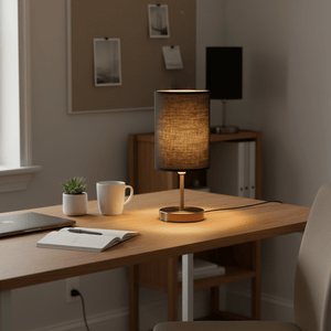 Antique brass table lamp with black shade on a wooden desk, alongside a notebook and coffee mug.