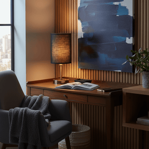 Antique brass table lamp with black shade on a wooden desk beside a cozy chair and decorative elements.