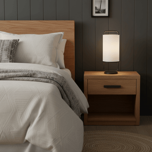 Watson Black & White Cylinder Table Lamp on a wooden nightstand beside a bed with textured bedding.