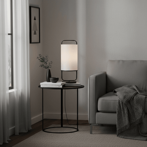 Watson Black & White Cylinder Table Lamp on a side table next to a grey sofa, with decorative items and a plant.