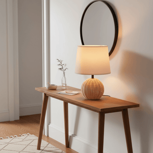 Ammeline Rattan & White Table Lamp on a wooden console table with a round mirror and decorative items.