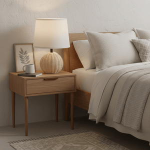 Ammeline Rattan & White Table Lamp on a bedside table with a cozy bed and decor elements.