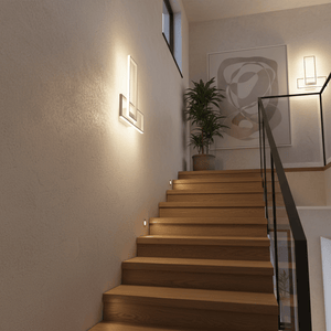Modern rectangular wall-mounted LED light fixture emitting warm illumination on a textured wall beside wooden stairs