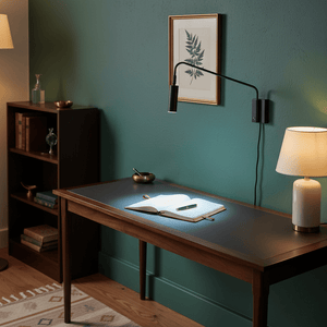 Corded LED reading light mounted above a desk, illuminating an open notebook with a pen, against a green wall.