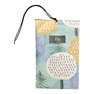 Patterned pine fragrance sachet with tree illustrations, black label, and hanging cord on white