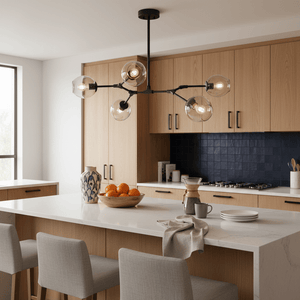 Ratanda 5 Light Black Pendant hanging over a kitchen island with wooden cabinets and a bowl of oranges.