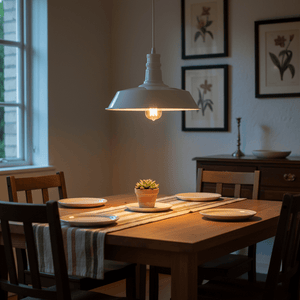 LED pendant light hanging over a wooden dining table set with plates and a small plant.