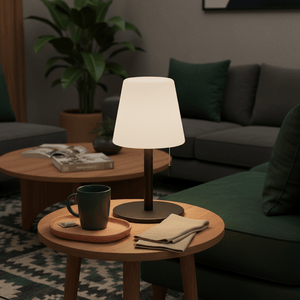 A modern table lamp on a wooden side table, surrounded by a cozy living room setting with green cushions.
