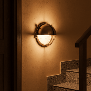 Antique brass outdoor wall light illuminating a staircase, showcasing its nautical design.