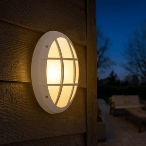 Close-up of the Fumagalli Danzi grey outdoor wall light mounted on a wooden surface, illuminating the surroundings.