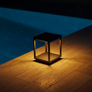 Decorative outdoor light on a stone ledge by a pool at night