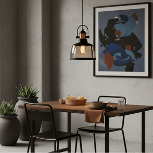 Metal pendant light with cognac glass above a wooden dining table, featuring a modern art piece in the background.