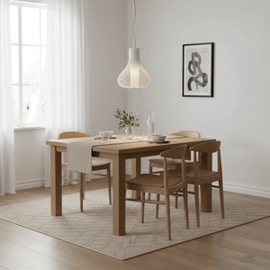 Scandi white pendant light hanging above a wooden dining table set with dishes and a vase.