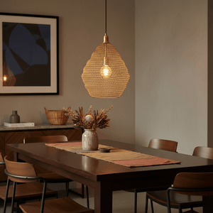 Gold mesh pendant light hanging above a dining table with floral centerpiece and wooden chairs.