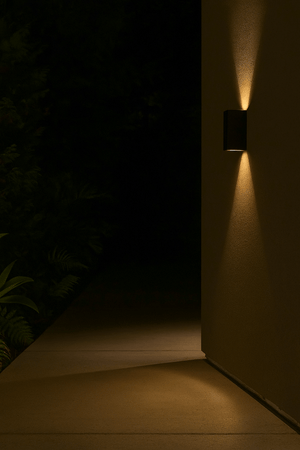 Wall-mounted light fixture casting a warm glow on a dark wall.