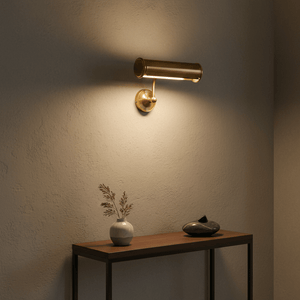 Antique brass wall lamp illuminating a textured wall above a wooden console table with decorative items.