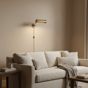 Antique brass wall lamp mounted above a light-colored sofa with decorative pillows and a throw.