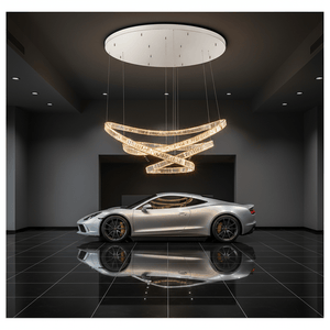 Modern chandelier hanging above a silver sports car in a dark room.