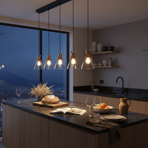 Five-light pendant light with clear glass shades illuminating a kitchen island at dusk.