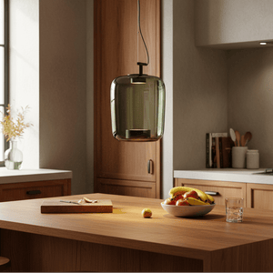Green glass pendant light hanging above a wooden kitchen island with fruits and a cutting board.