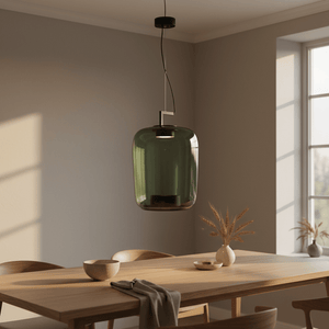 Green glass pendant light hanging above a wooden dining table with decorative elements.