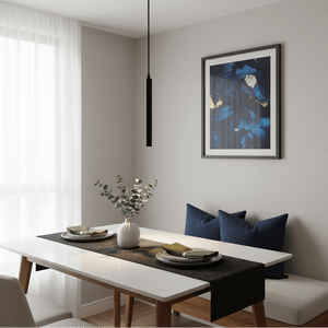 A slim black LED pendant light hangs above a dining table set with plates and greenery, enhancing a modern interior.