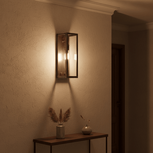 Antique silver outdoor wall light mounted on a textured wall, illuminating a wooden console table with decor.