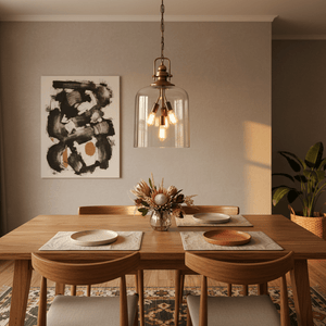 Satin brass pendant light with amber glass shades hanging over a wooden dining table with floral centerpiece.