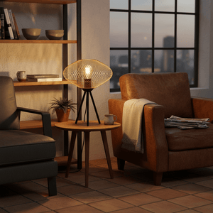 Slade Gold Mesh Table Lamp on a wooden side table beside a leather armchair, creating a cozy ambiance.