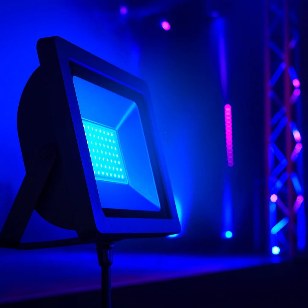 Close-up of a blue 50W floodlight illuminating a stage with vibrant blue and purple lighting.