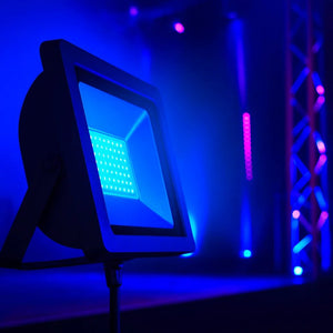 Close-up of a blue 50W floodlight illuminating a stage with vibrant blue and purple lighting.