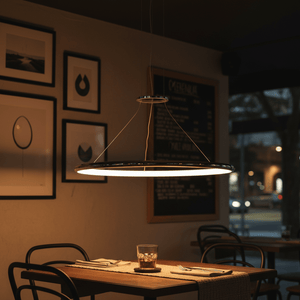 Sleek chrome LED ring pendant light hanging above a dining table, creating a warm ambiance.