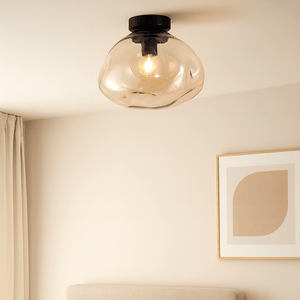 Neatly made bed with pillows, nightstand with lamp, and framed artwork on a wall in a bedroom.