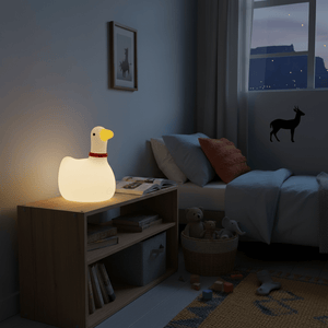 A soft-glowing goose night light on a wooden nightstand in a cozy child's bedroom.