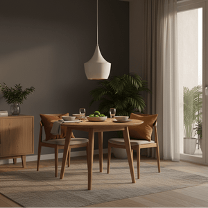 A modern dining setup featuring a white metal pendant light above a round wooden table with green fruit and glasses.