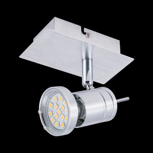 Brushed aluminium adjustable spotlight head angled below rectangular ceiling plate on black background
