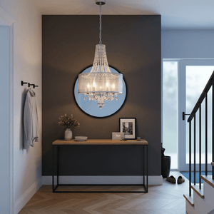 Polished chrome crystal chandelier hanging above a wooden console table in a stylish entryway.