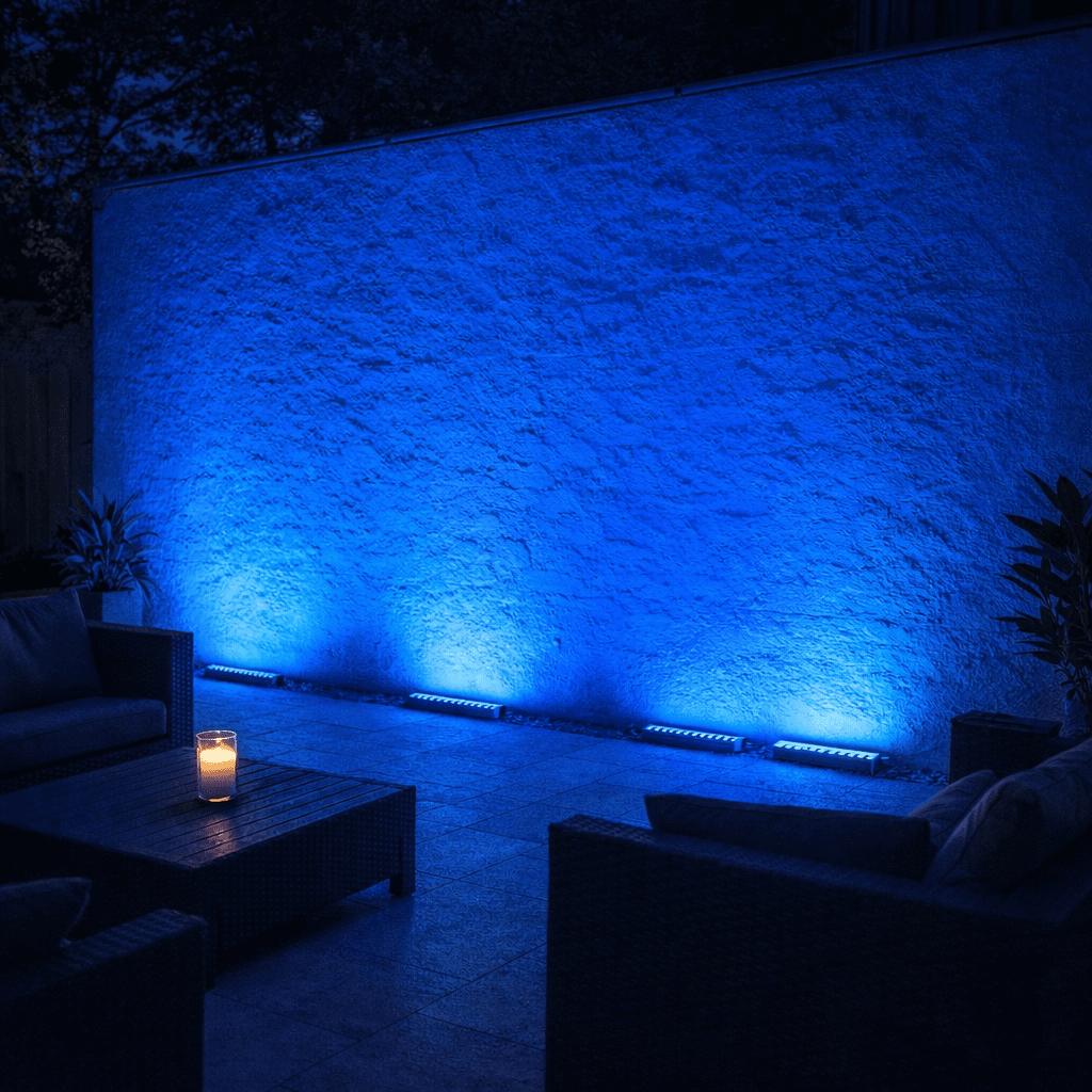 Outdoor setting with a textured wall illuminated by blue wall washer lights, featuring modern furniture.