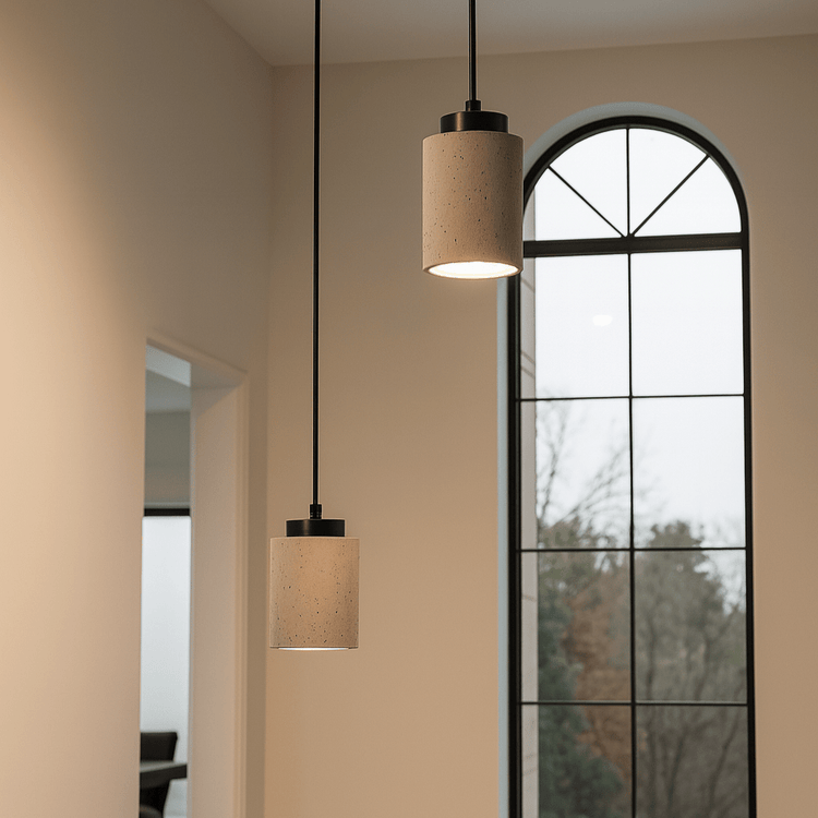 Two pendant lights hanging from the ceiling in a room with a large window.