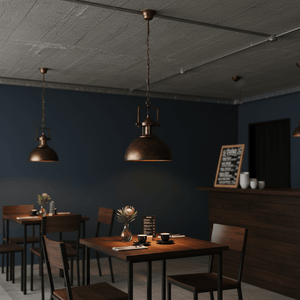 Stylish black and gold pendant light hanging over a wooden dining table in a modern café setting.