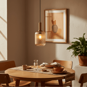 Athina Amber Cut Glass Pendant hanging above a dining table set with plates and a plant in the background.
